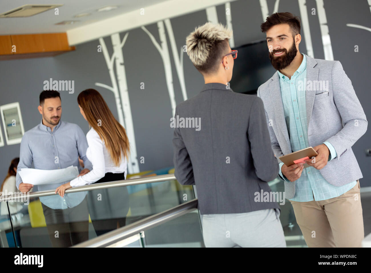 Business people discussing over documents in office lobby. Stock Photo