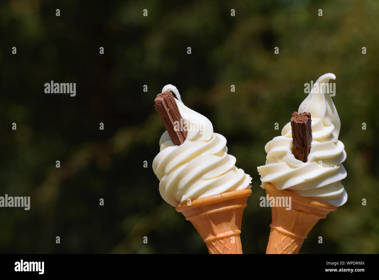 Two ice cream cones filled with soft whipped vanilla ice cream and chocolate flakes Stock Photo