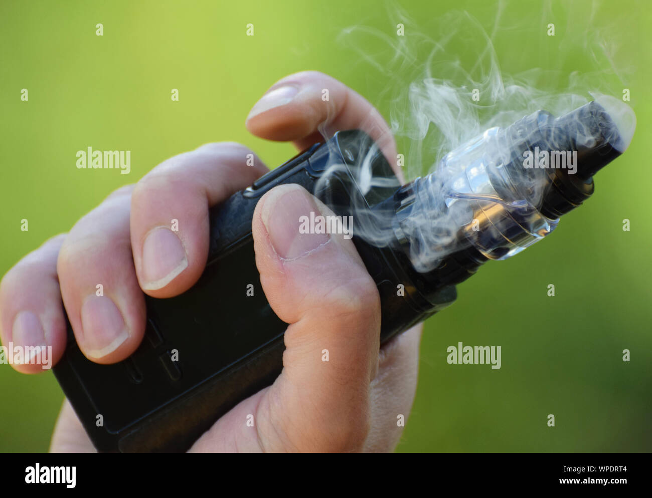 An E Cigarette / Mod in the hand of a man vaping close up photo Stock Photo