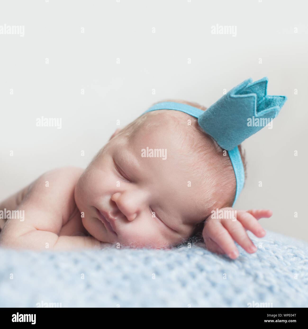 Beautiful newborn baby girl in blue crown, closeup portrait Stock Photo