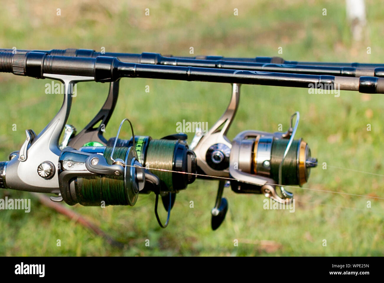 Closeup of a reel fishing rod on a prop and water background Stock Photo -  Alamy
