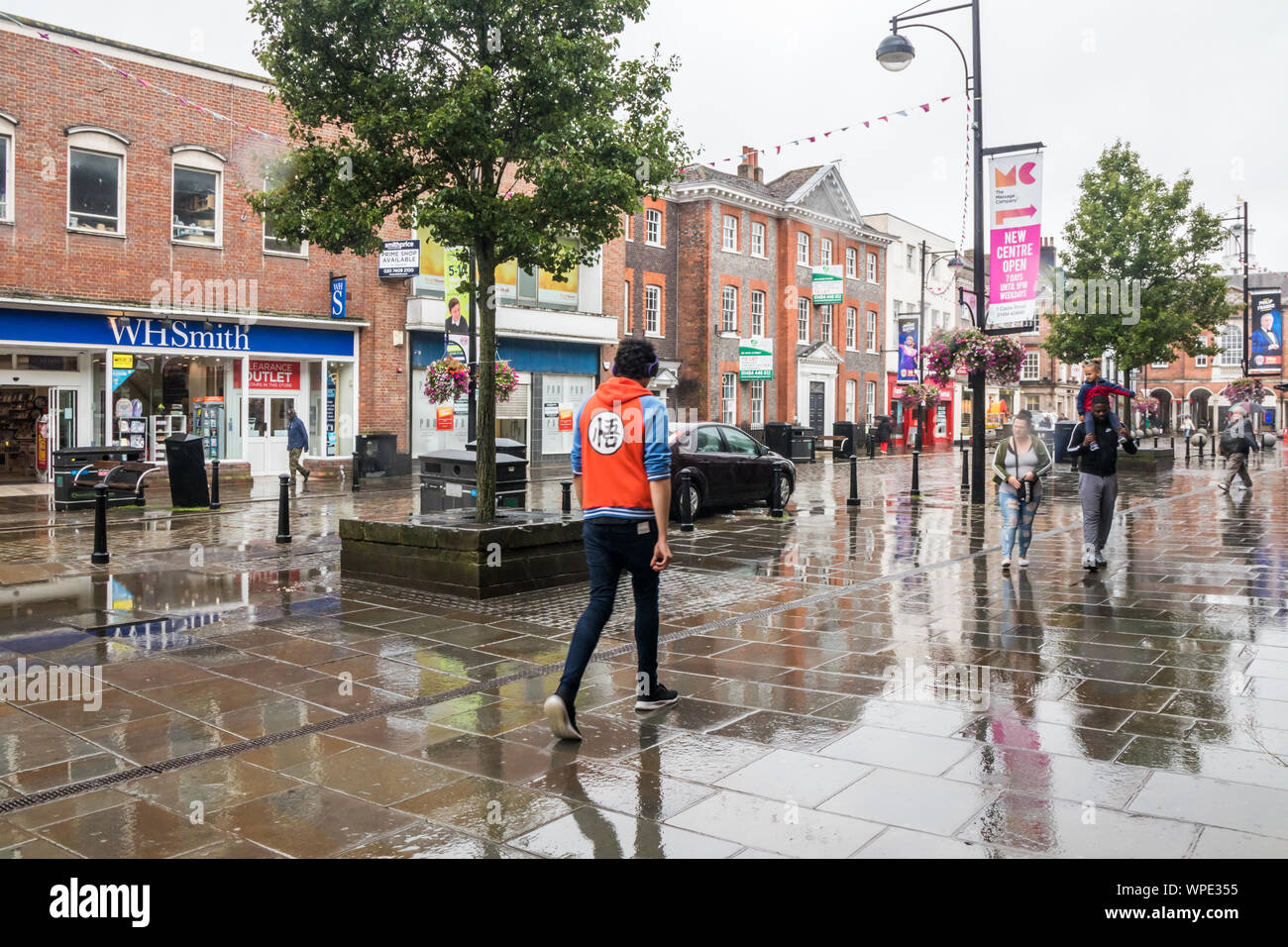 High Wycombe, Engalnd - August 14th 2019: People walking down the High Street in the rain. It frequently rains in the summer. Stock Photo