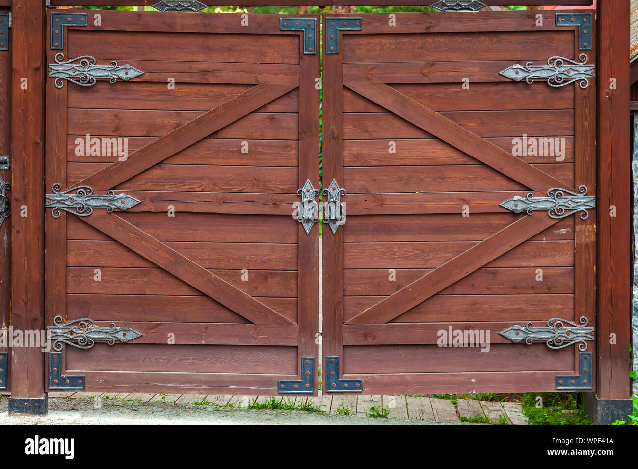 Close-up on a brown wooden gate with wrought iron hinged patterns Stock ...