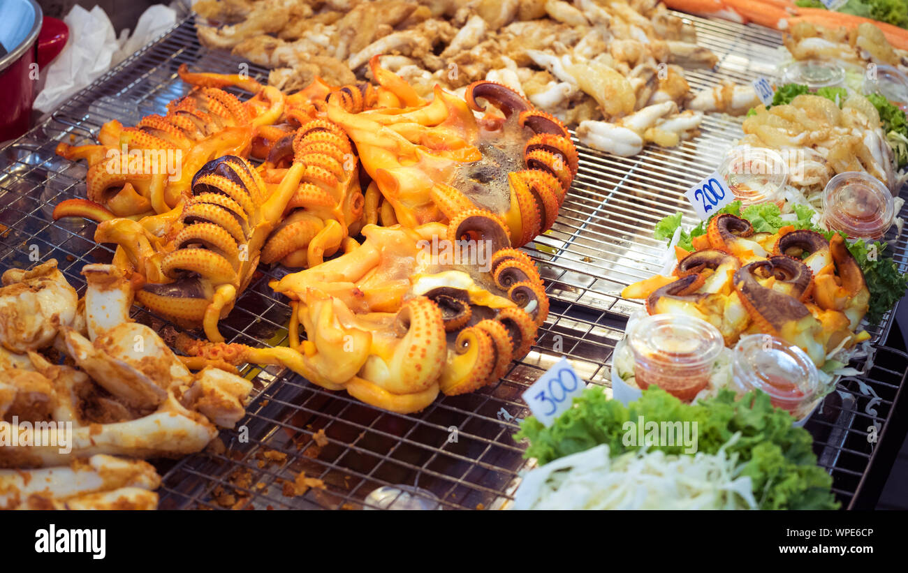 Savory grilled octopus on the grate at a street food market at Asiatique The Riverfront in Bangkok, Thailand. Stock Photo