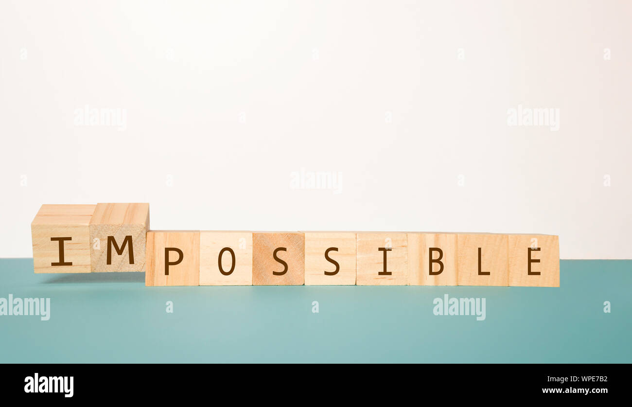 Flipping two wooden cube to change the word Impossible to Possible on neutral background Stock Photo