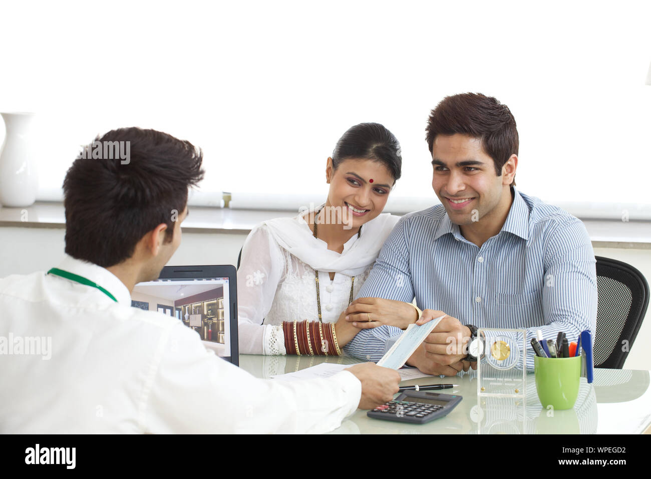 Bank manager giving loan cheque to young couple Stock Photo - Alamy