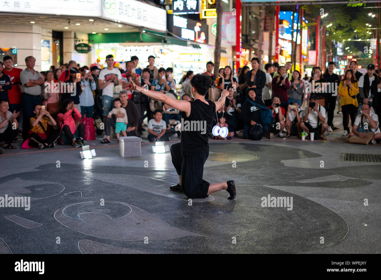 Taipei, Taiwan: Taiwanese street performer demonstrating amazing skill with a glowing, illuminated Diabolo in Ximen Ding shopping district Stock Photo