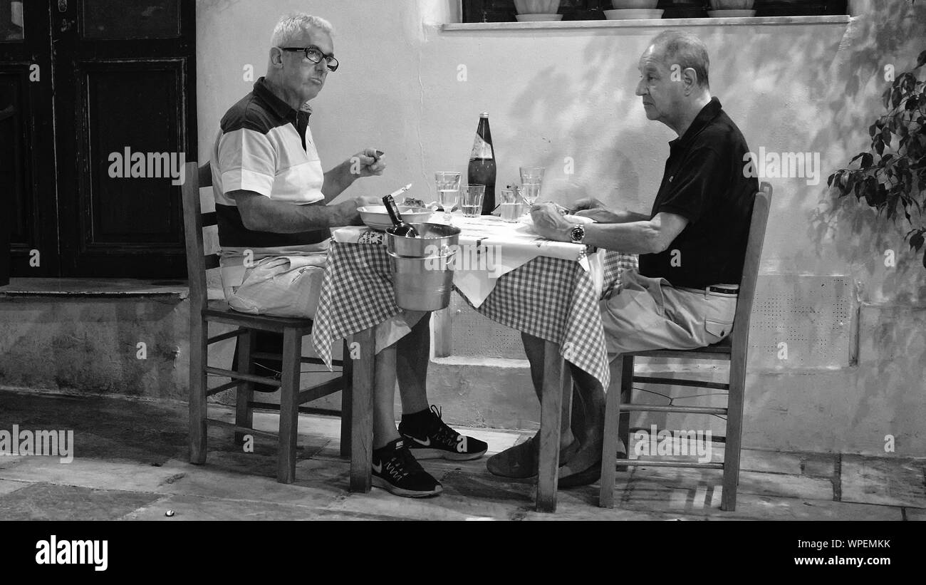 Two older men eating dinner together in Athens, Greece. Stock Photo