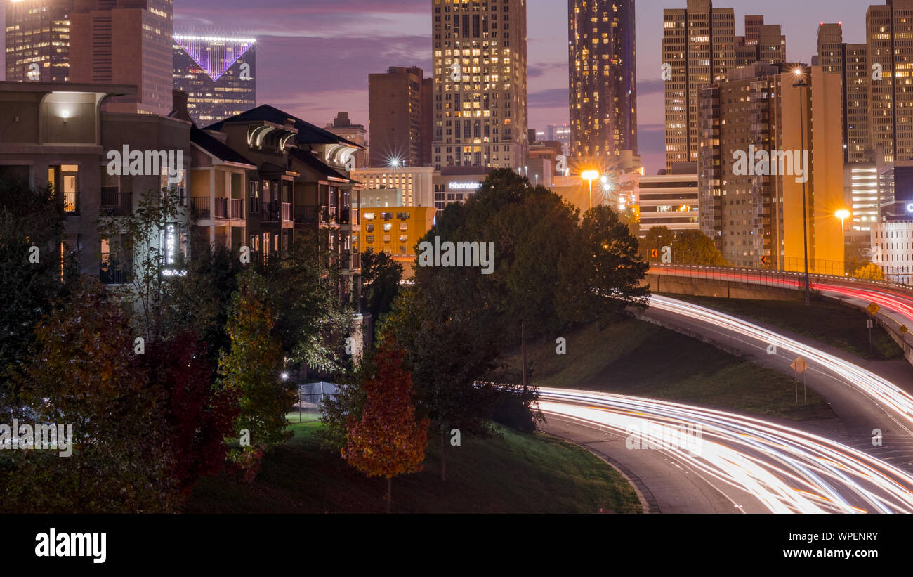 Urban city skyline at night with cars going by. Stock Photo