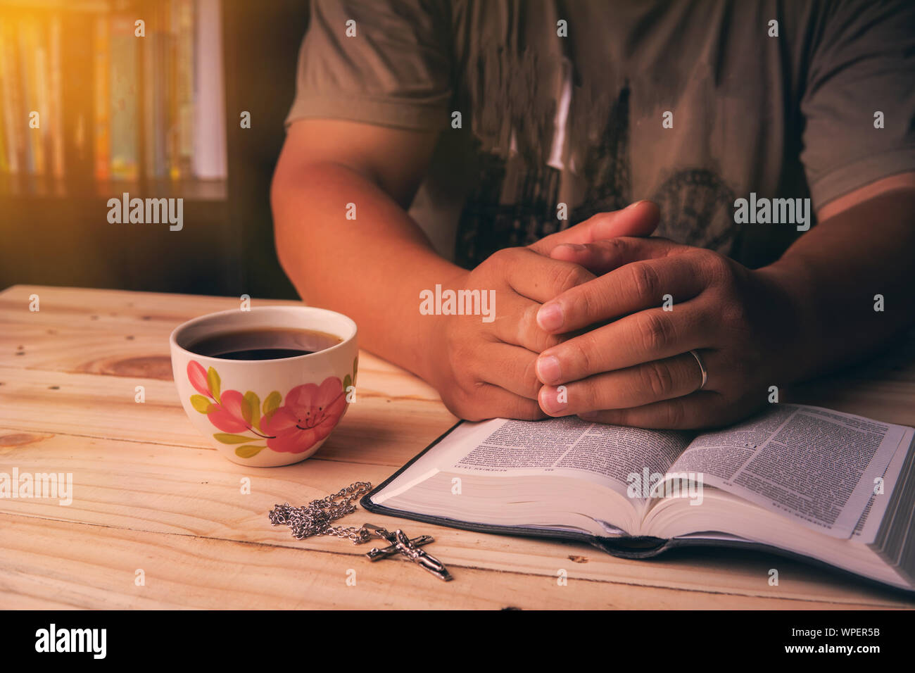 Christian man Bible study. Christian hand while praying and worship for christian religion with blurred of her body background, Casual man praying wit Stock Photo