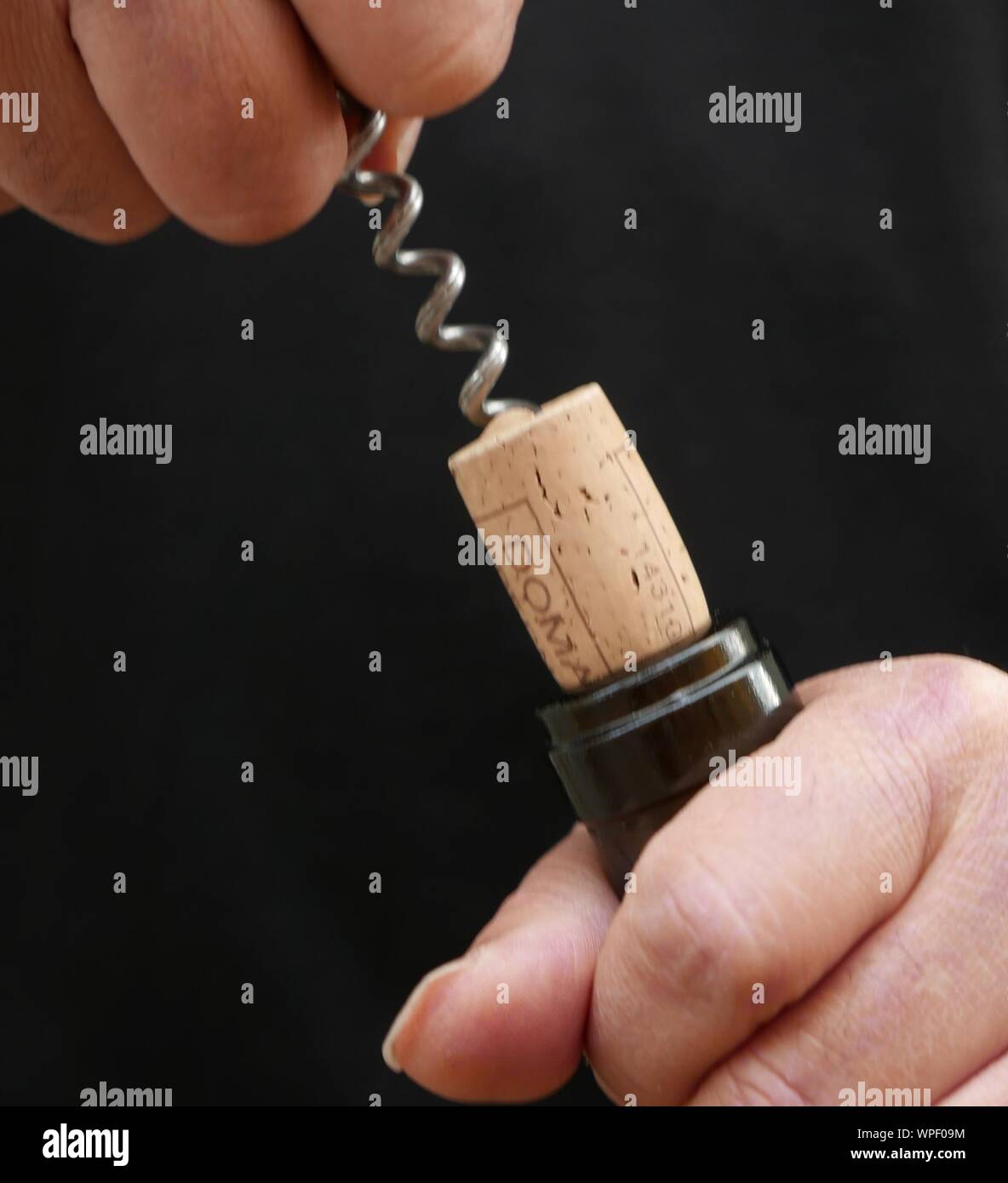 Midsection Of Man Pulling Cork From Wine Bottle Stock Photo