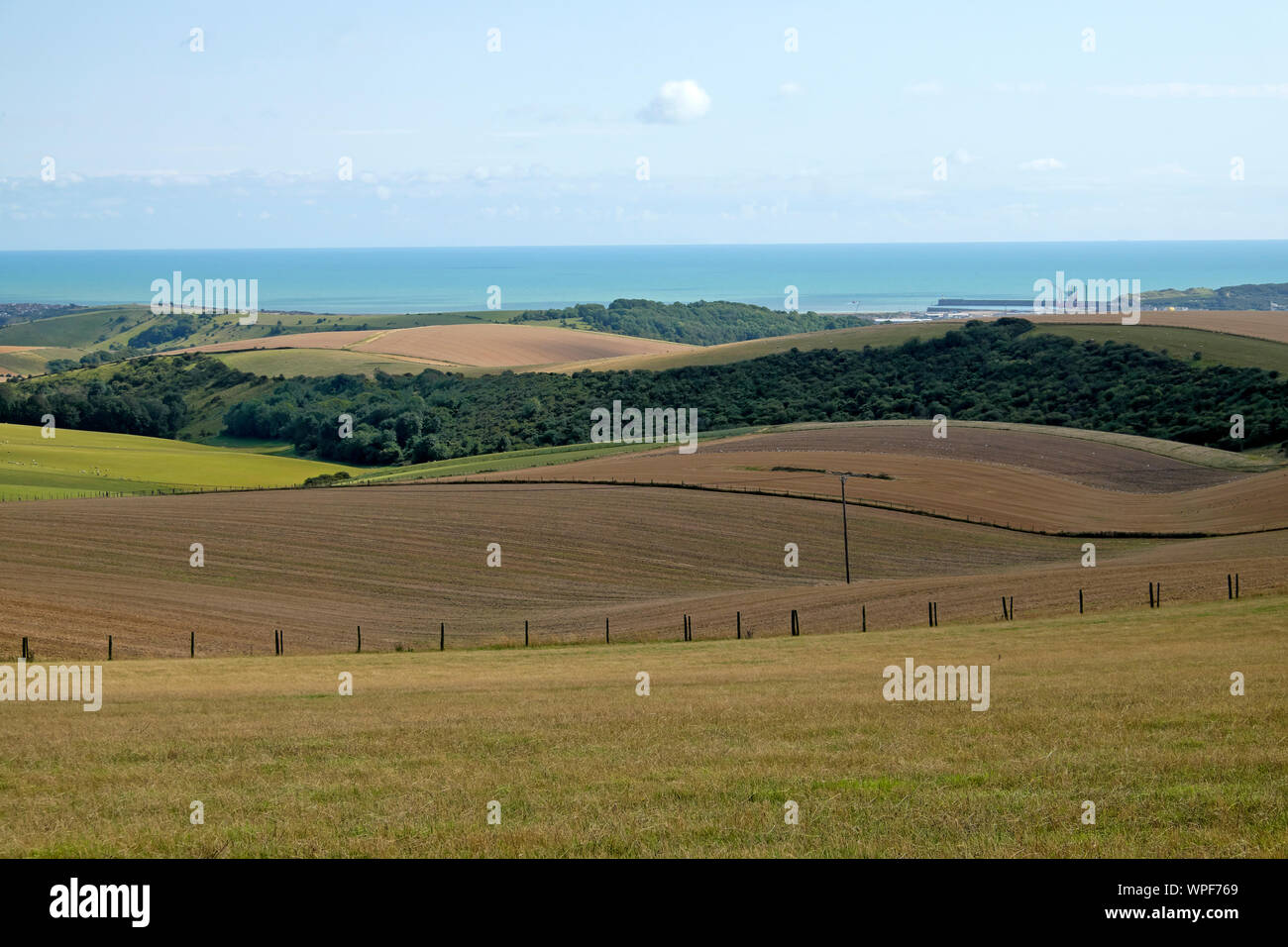 View over farmland and rolling hills looking towards sea and Port of Newhaven in summer from South Downs Way in East Sussex, England UK  KATHY DEWITT Stock Photo