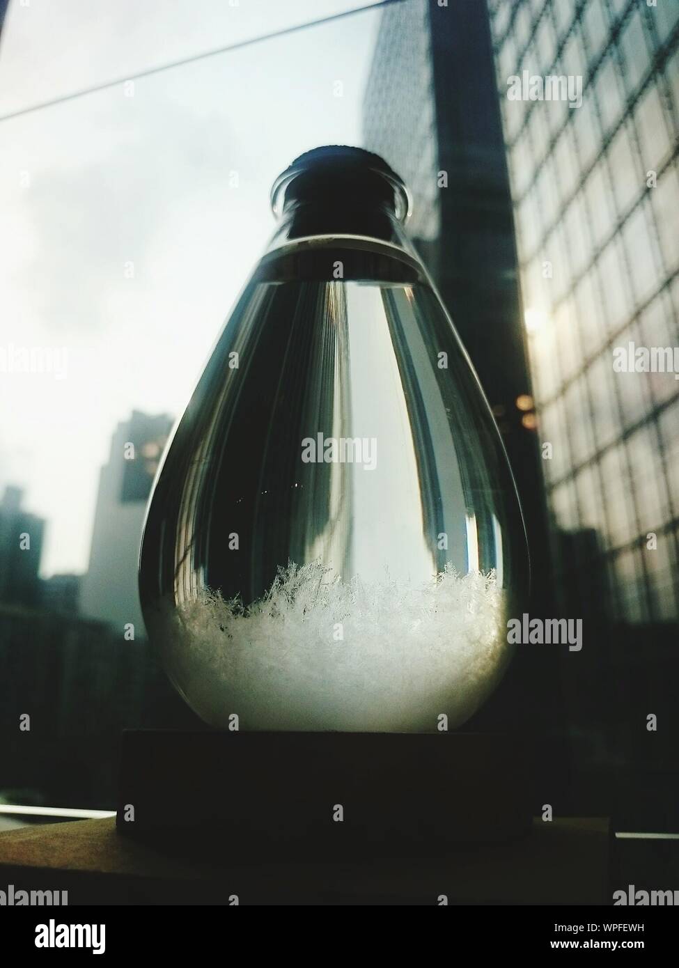 Partially Frozen Water In Glass Pottle Against City Scape Stock Photo