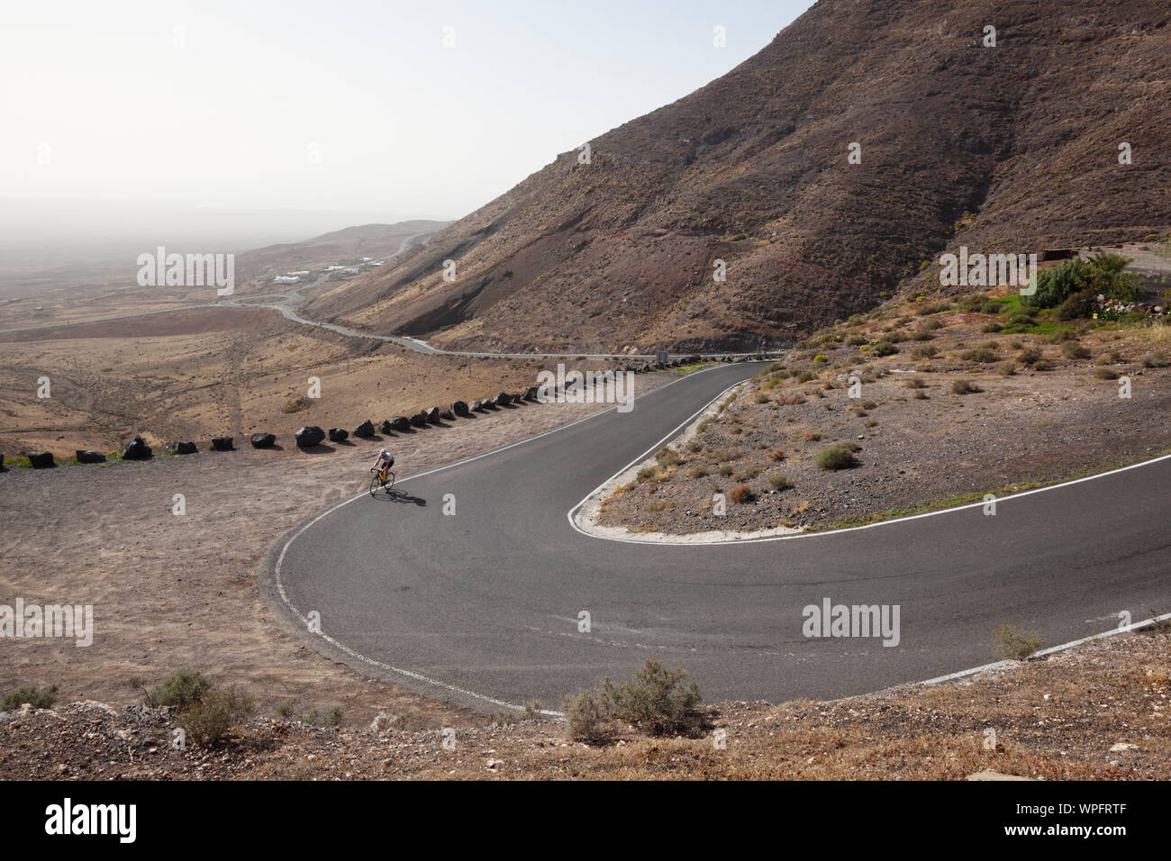 Lone Cyclist on the climb to Femes. Lanzarote. Canary Islands. Stock Photo