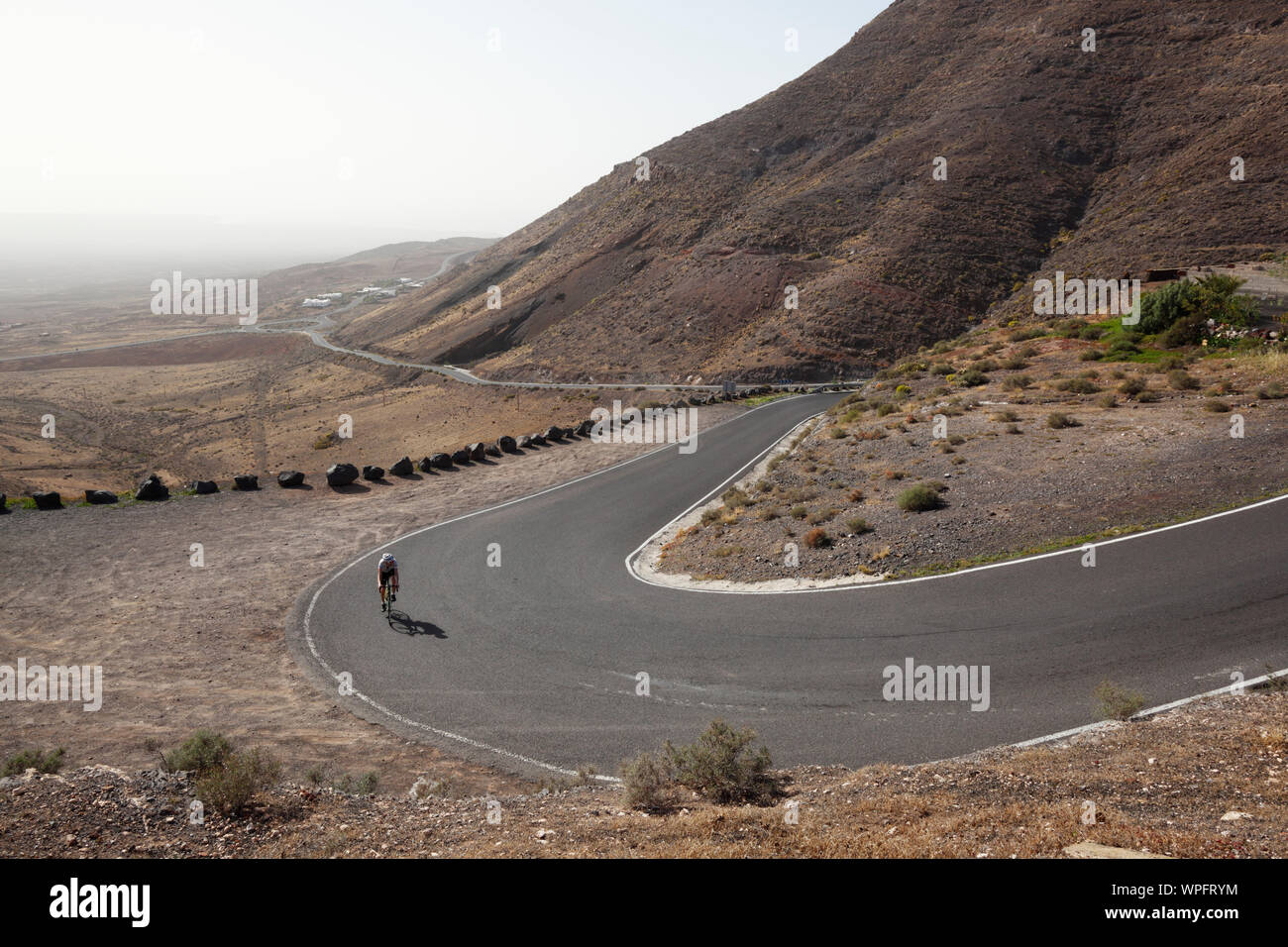 Male cyclist climbing the steep road to Femes. Lanzarote. Canary Islands. Spain. Stock Photo