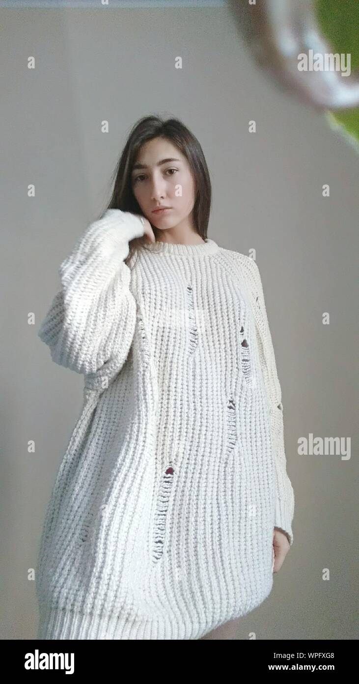 Portrait Of Young Woman Wearing White Sweater Against Gray Background Stock Photo