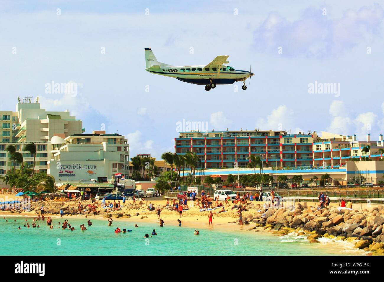 A St Barth Commuter F-0SBH Cessna Caravan propeller plane, flies low over Maho beach as it comes in to land at SXM Princess Juliana Airport. Stock Photo