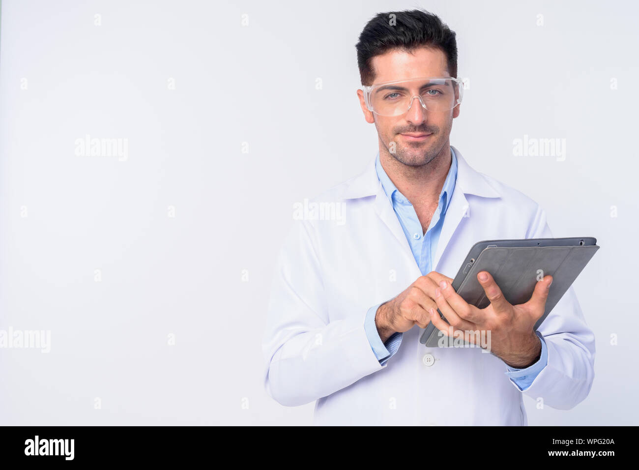 Young handsome man doctor with protective glasses using digital tablet Stock Photo