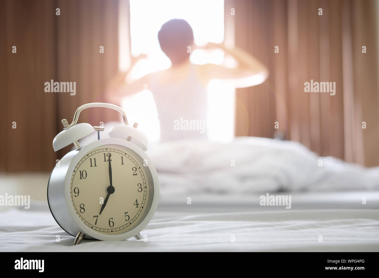 The alarm clocks in the morning, causing the woman to wake up and twist