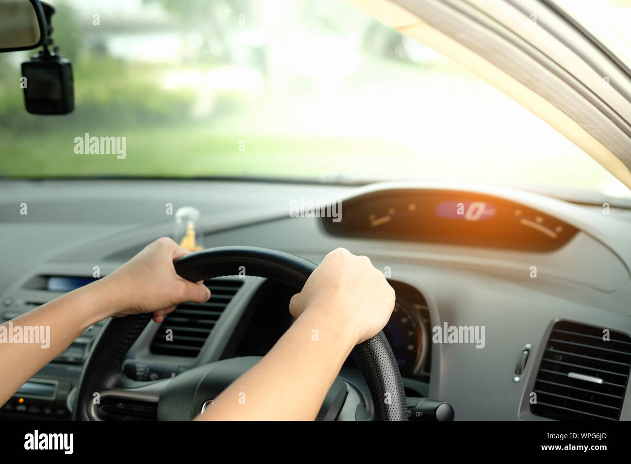 The hands are holding the steering wheel and driving on a light day. Stock Photo