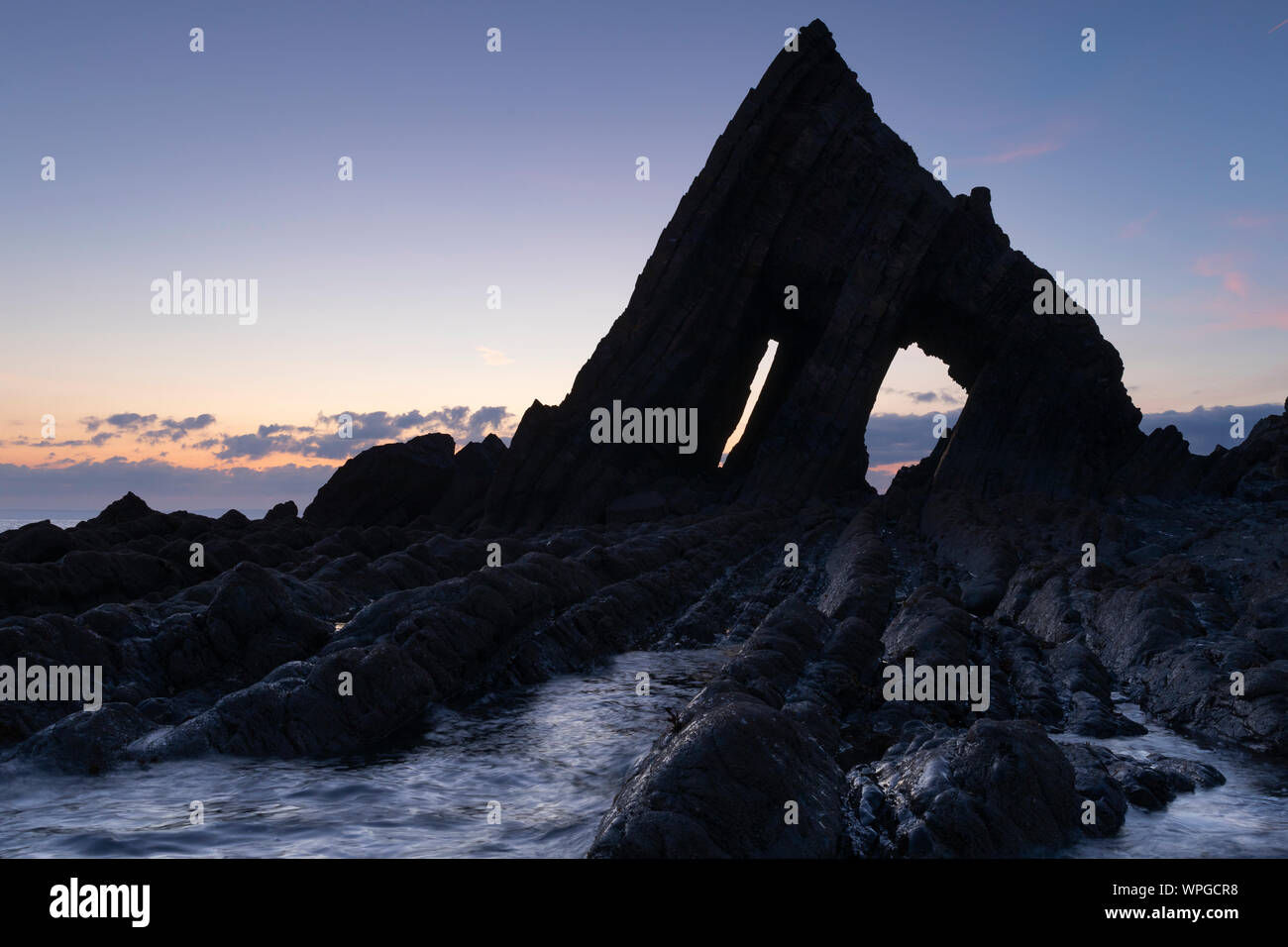 Blackchurch Rock at Mouthmill Beach on the North Devon coast silhouetted against the dawn sky Stock Photo