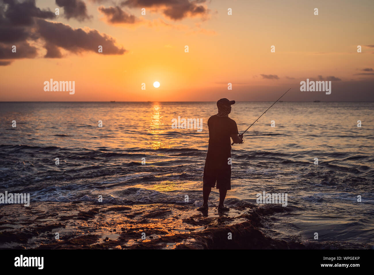 Fisherman fishes in the sea at sunset Stock Photo - Alamy