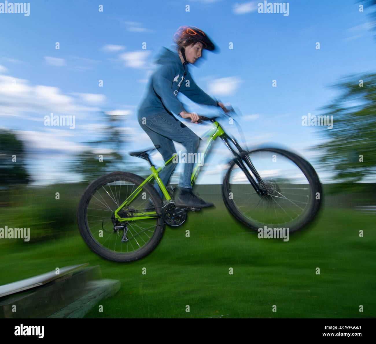 Teenage boy doing jumps on bike in back garden Stock Photo Alamy