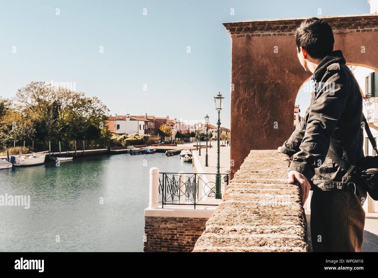 Man Looking Away While Standing By Railing At Lido Di Venezia Against Clear Sky Stock Photo