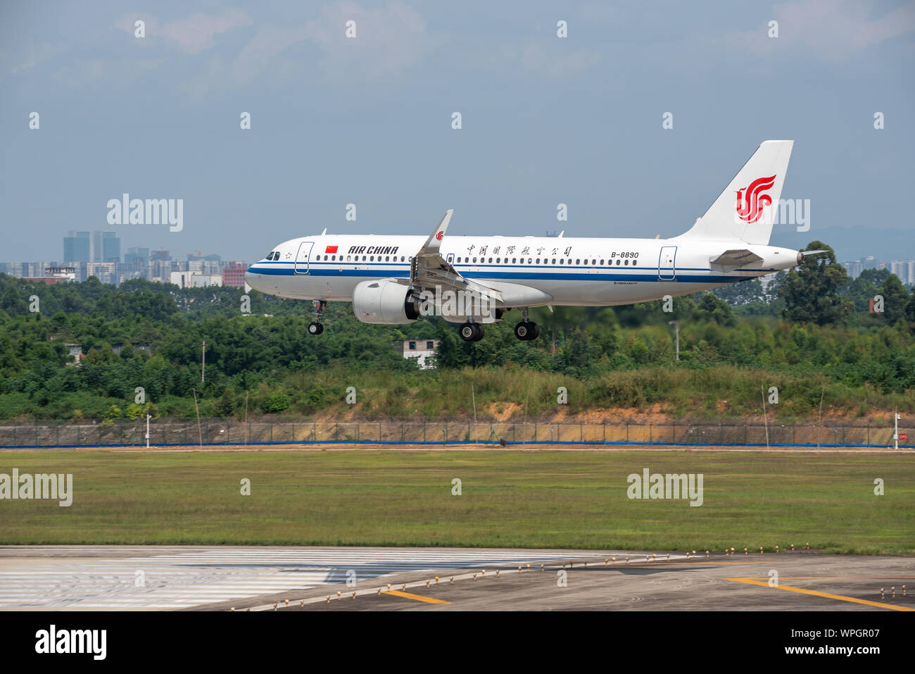 Chengdu airport, Sichuan province, China - August 28, 2019 : Air China Airbus A320 Neo commercial airplane landing in Chengdu with the city in the background Stock Photo