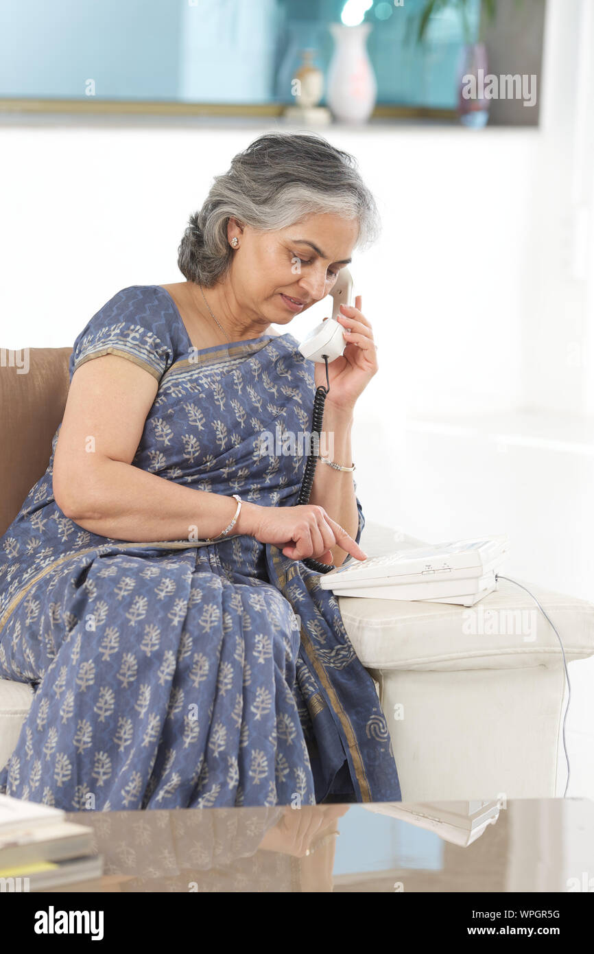 Senior woman dialing on a landline phone Stock Photo