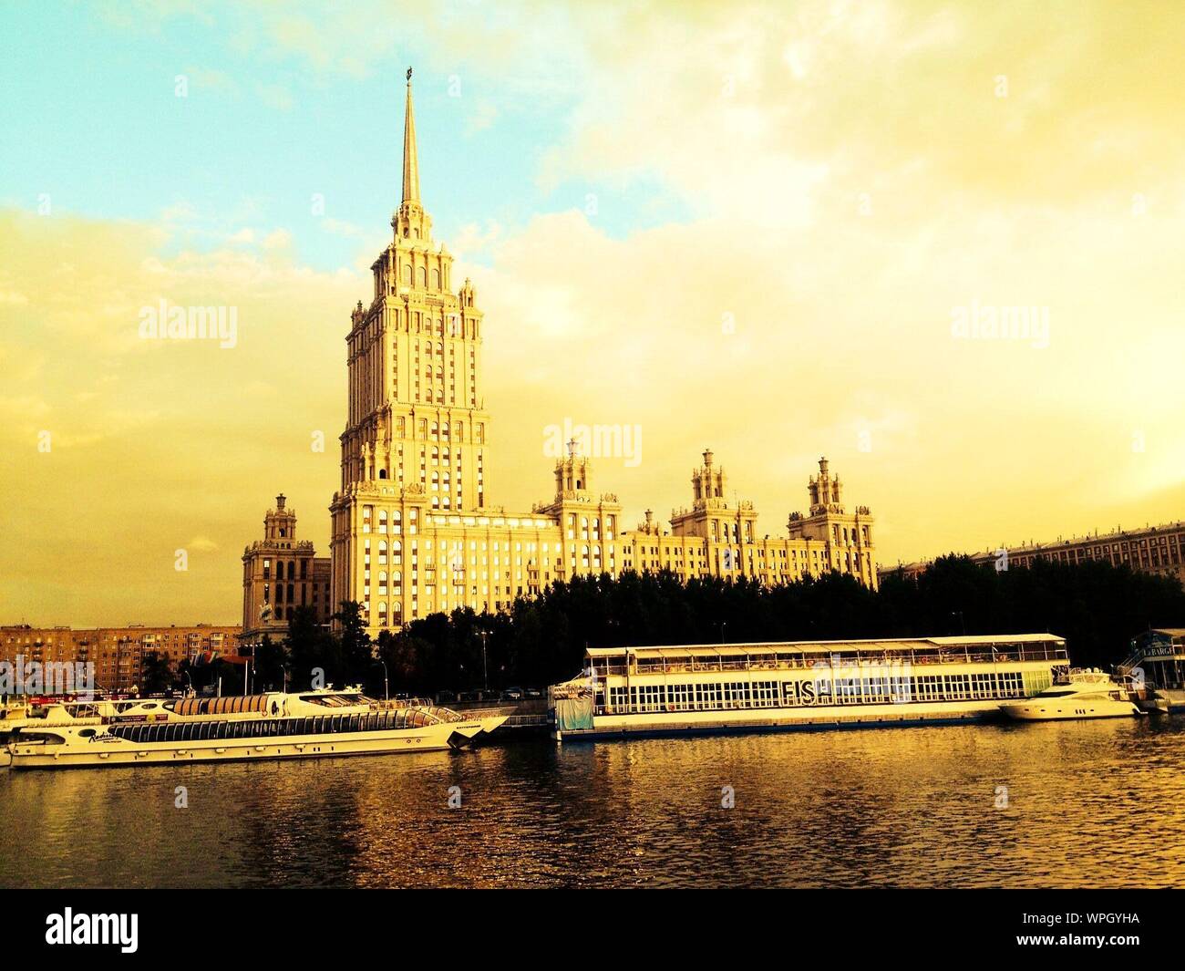 Ferry Boats On Moscva River By Hotel Ukraina Against Cloudy Sky Stock Photo