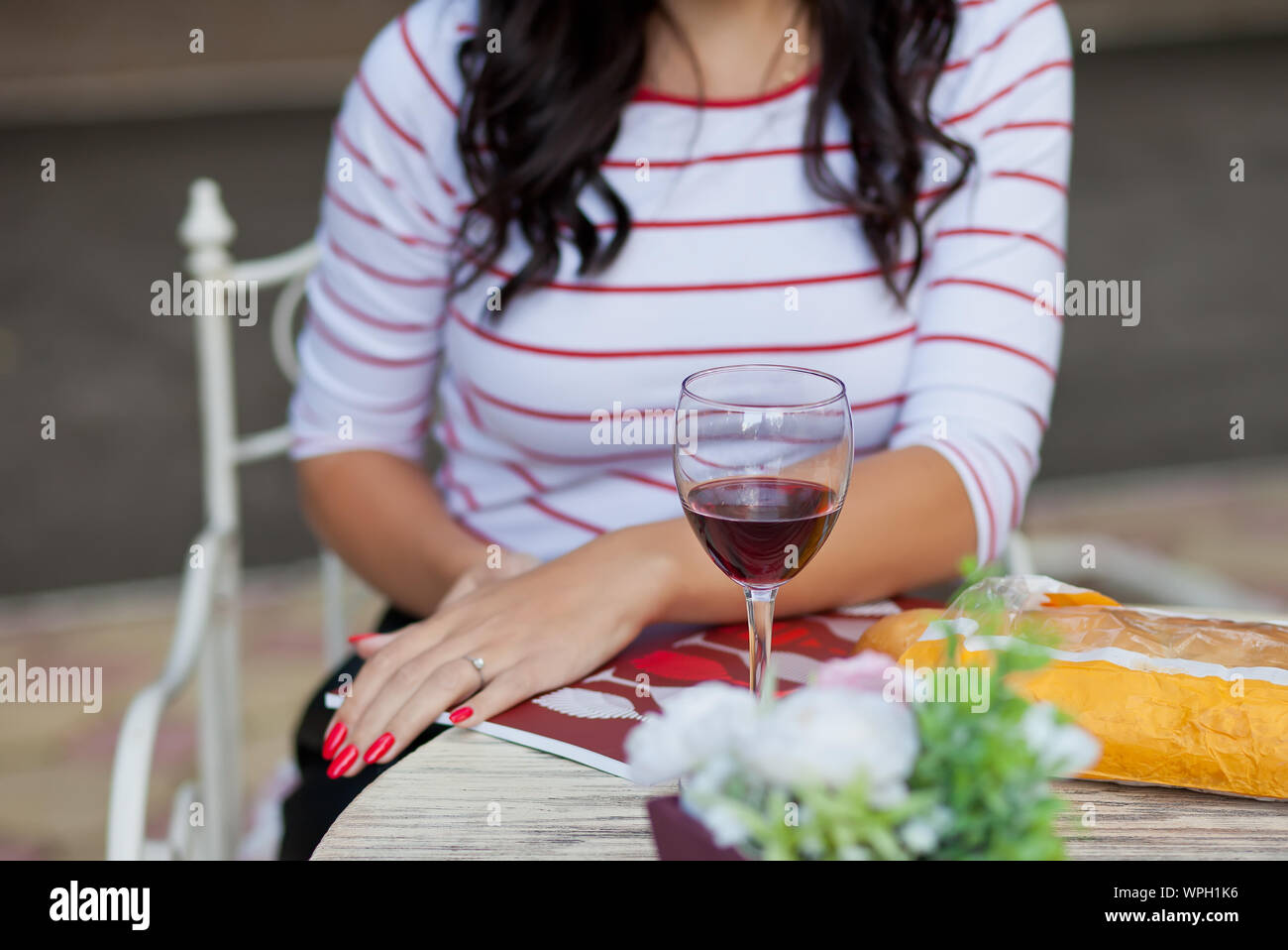 Pretty brunette woman in a striped t-shirt drinking red wine in outdoor ...
