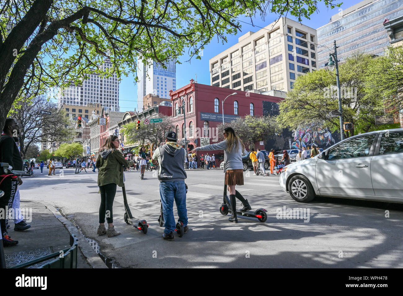 People ride e-scooters on Sixth Street in Austin Texas during SXSW festival in March 2019. Stock Photo