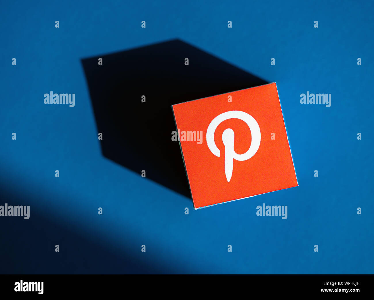 Kyiv, Ukraine - September 9, 2019: A shot from above of paper cube with the printed logotype of the Pinterest application, that placed on a blue backg Stock Photo
