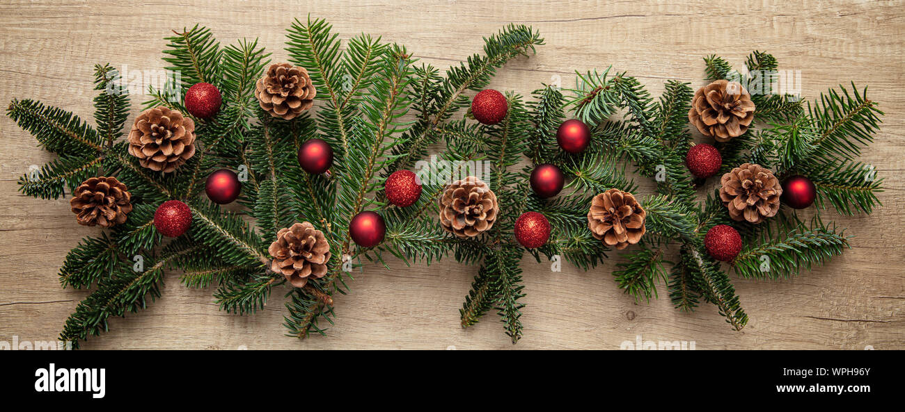 green Christmas tree decorated with red toys, ornaments, pine cones, beads  garlands box sofa wooden wall floor Stock Photo - Alamy