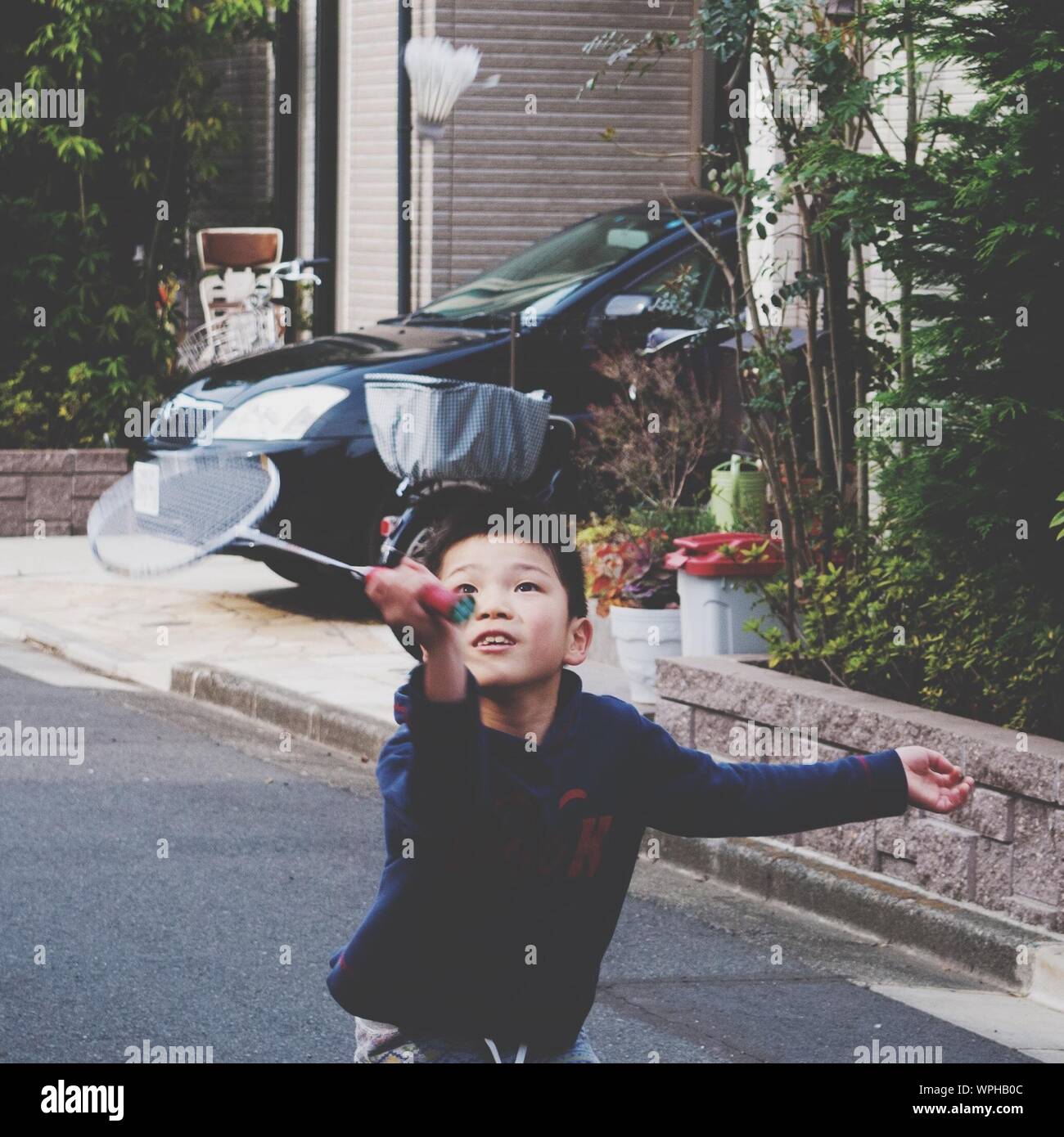Boy Playing Badminton On Street By House Stock Photo