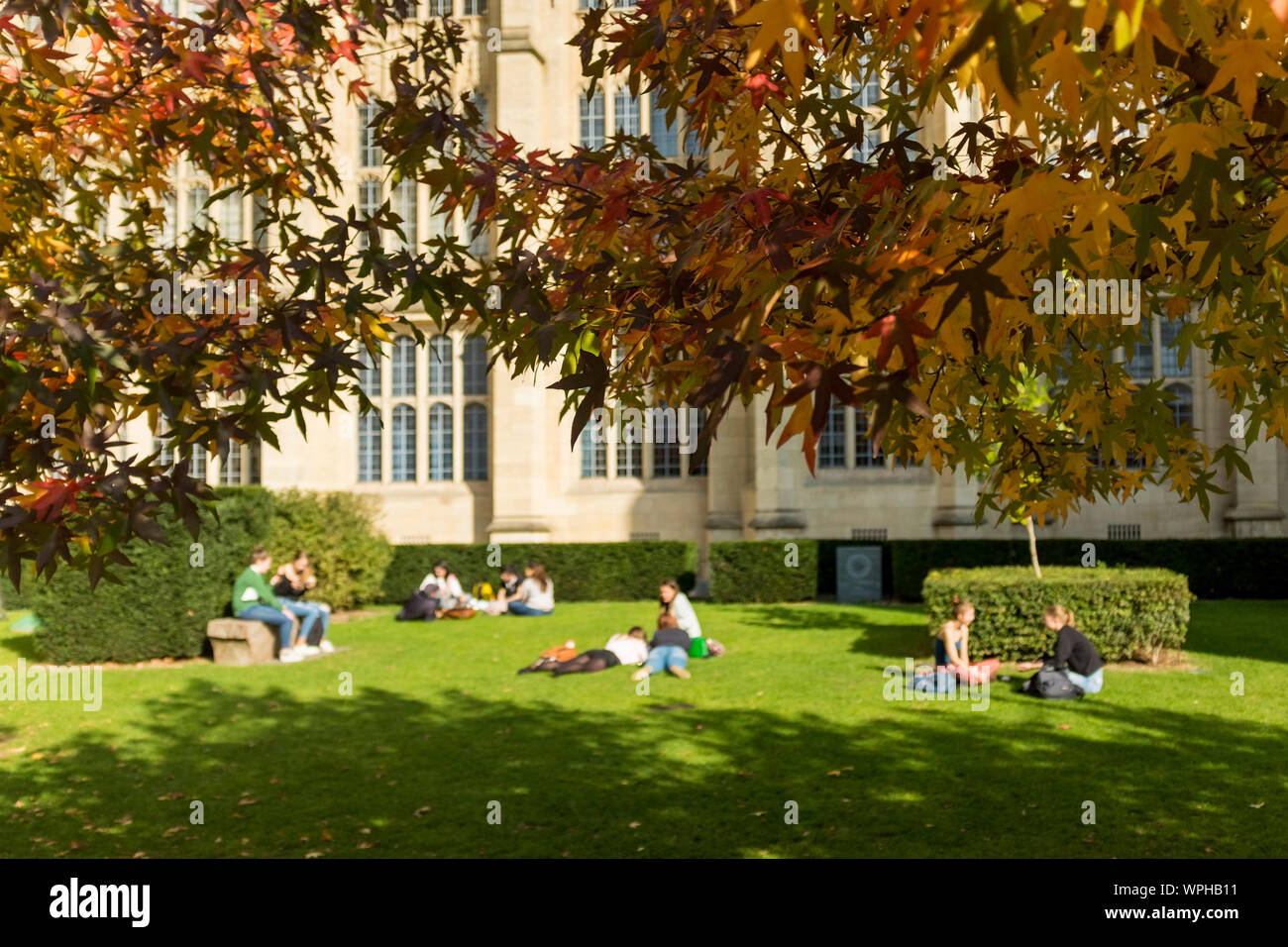 Student of University of Bristol enjoying sunny day sitting or lying on grass, Bristol, UK (students out of focus.  See WPHB19 for students in focus) Stock Photo
