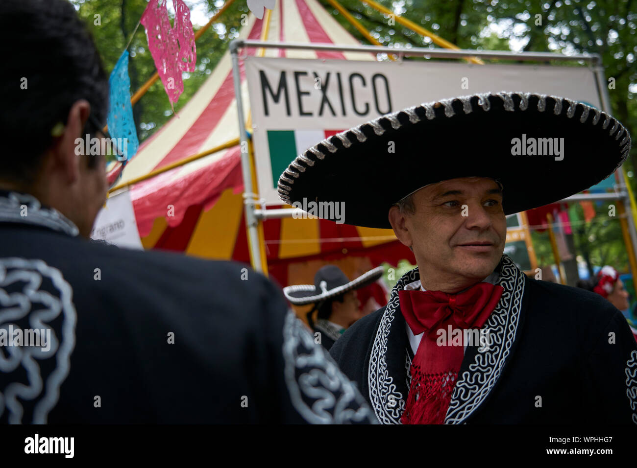 Two men pose in the typical charro costume in front of the Mexican stand. Stock Photo