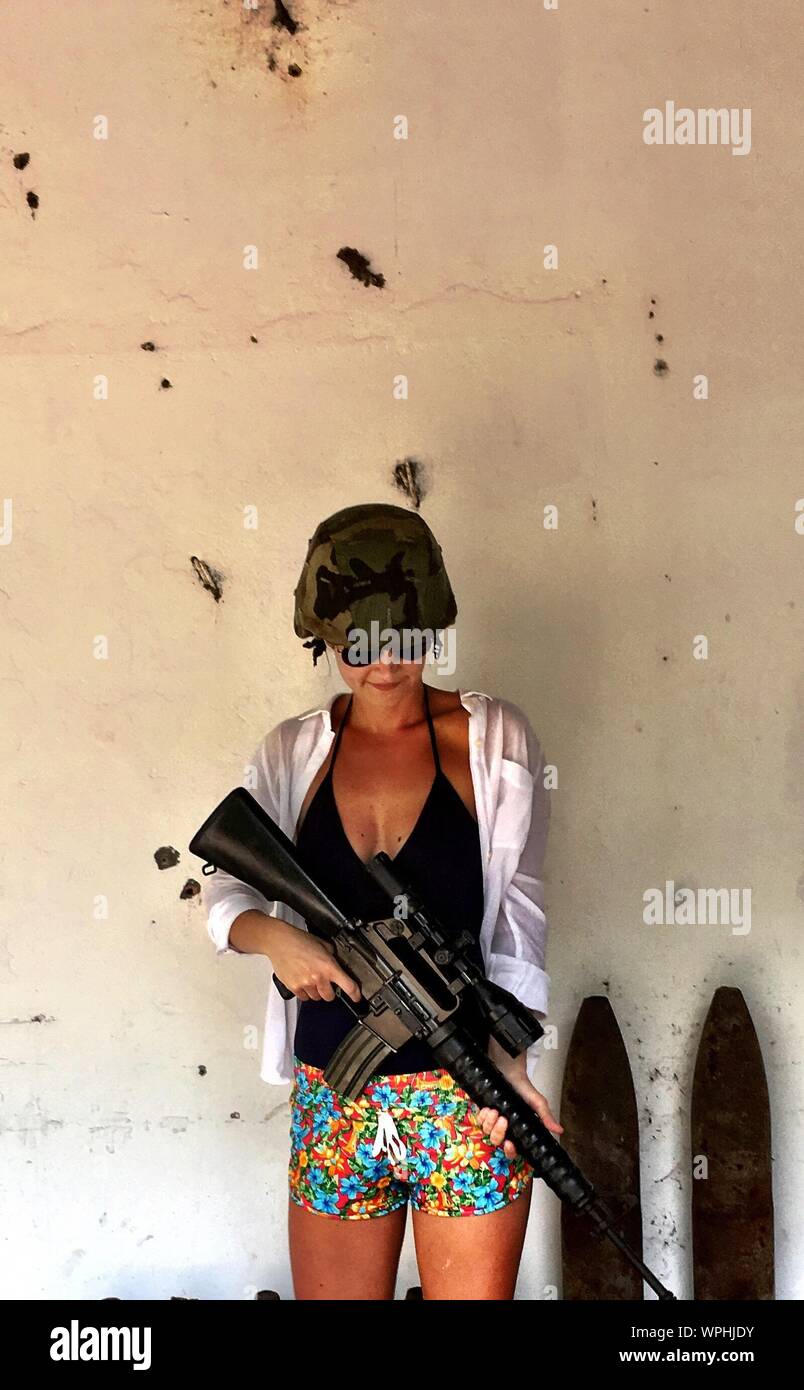 Woman Holding Ak-47 While Standing Against Wall Stock Photo