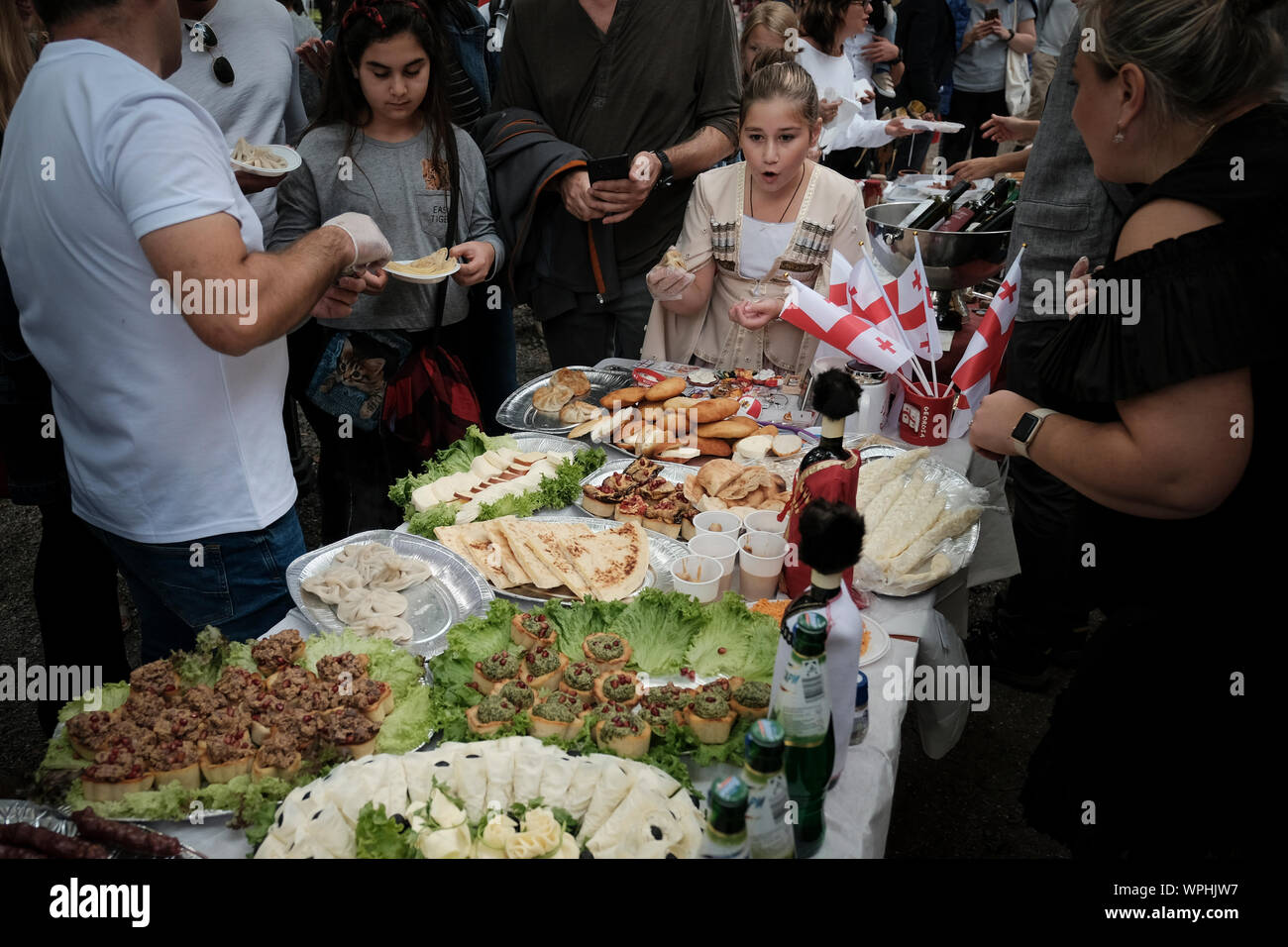 A girl contemplates a huge table full of typical Georgian gastronomic dishes. Stock Photo