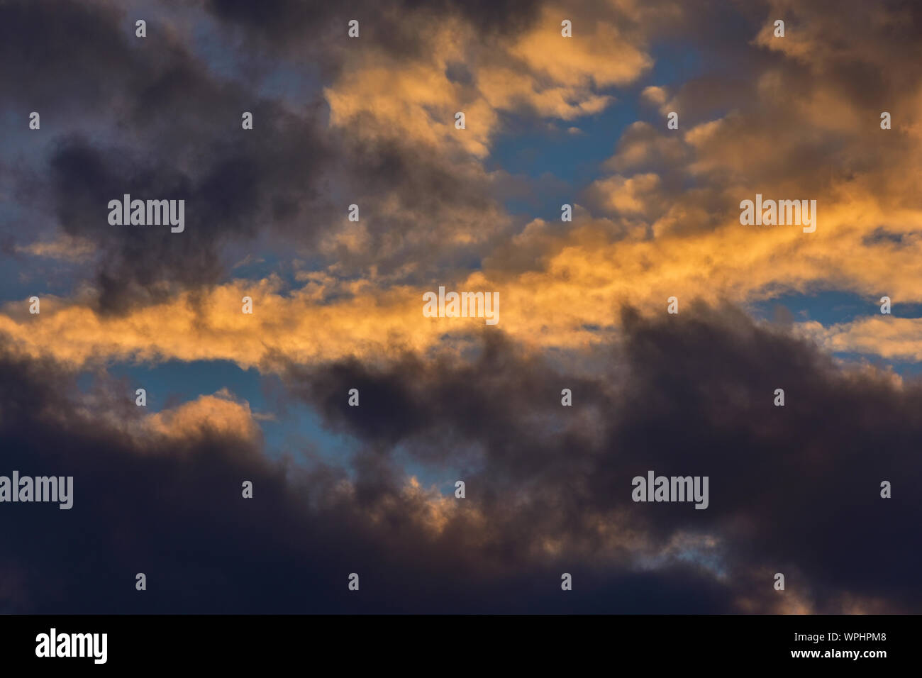 Sunset sky with golden and dark clouds as background Stock Photo - Alamy
