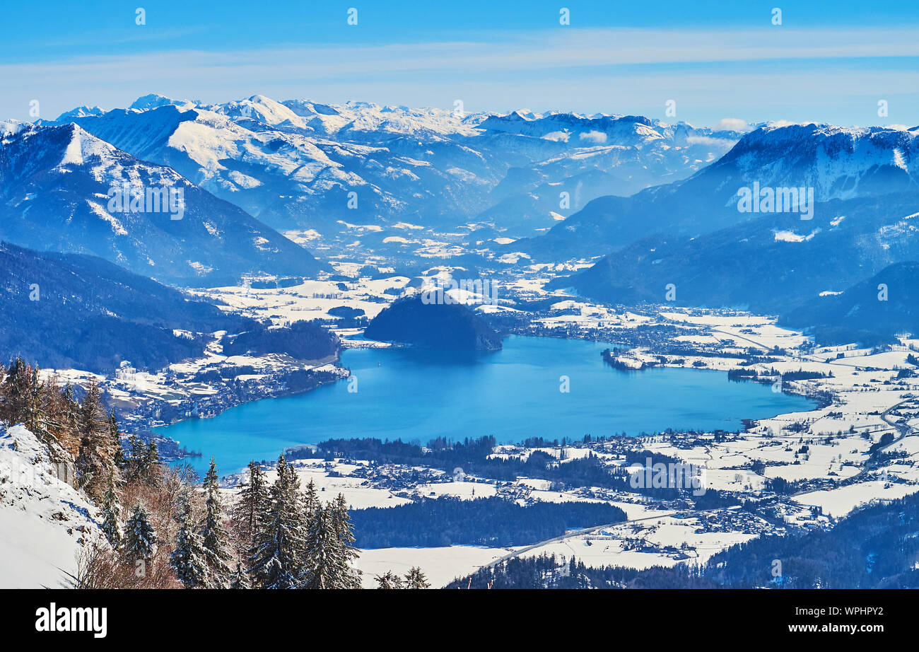 Observe the winter scenery of Inner Salzkammergut Alps and mirror turquoise surface of Wolfgangsee lake, seen in valley, from the top of Zwolferhorn, Stock Photo