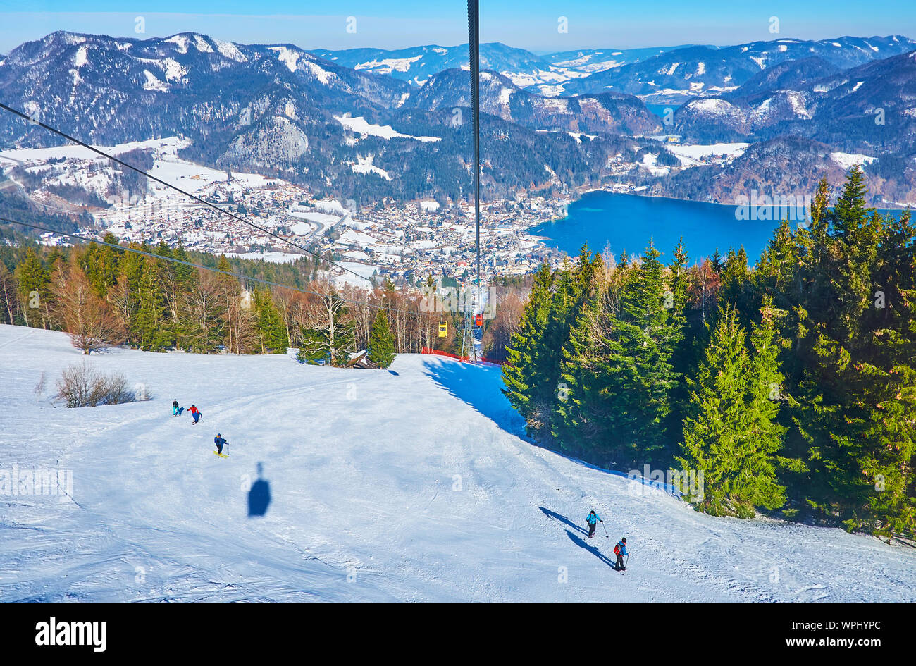 Ride the vintage Zwolferhorn cable car and observe the landscape of Salzkammergut, mountain lake of Wolfgangsee, lush coniferous forests on snowy slop Stock Photo