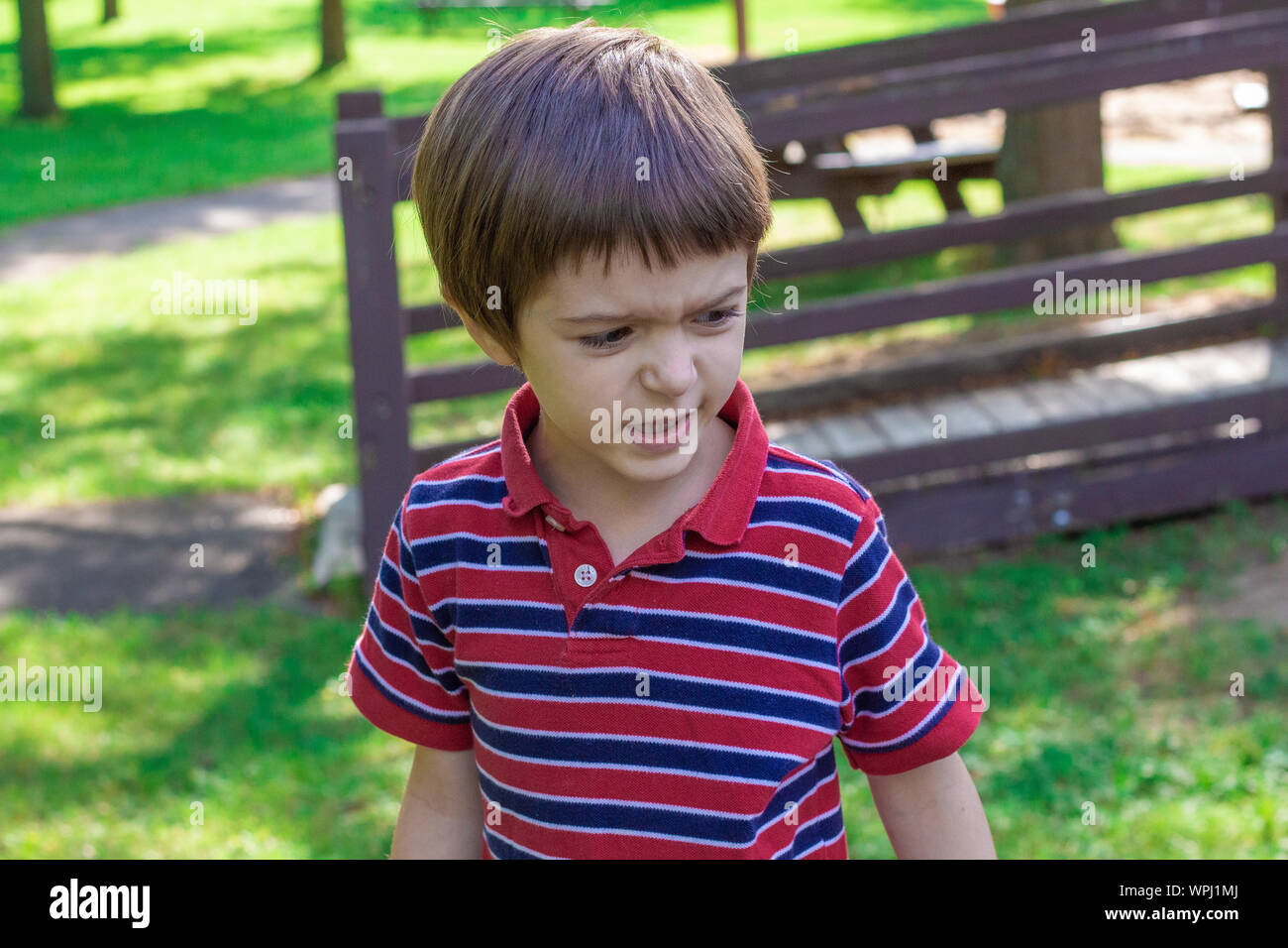 A little boy looks surprised and confused as he reacts to something. His facial expression has his face all scrunched up as he prepares to respond. Stock Photo