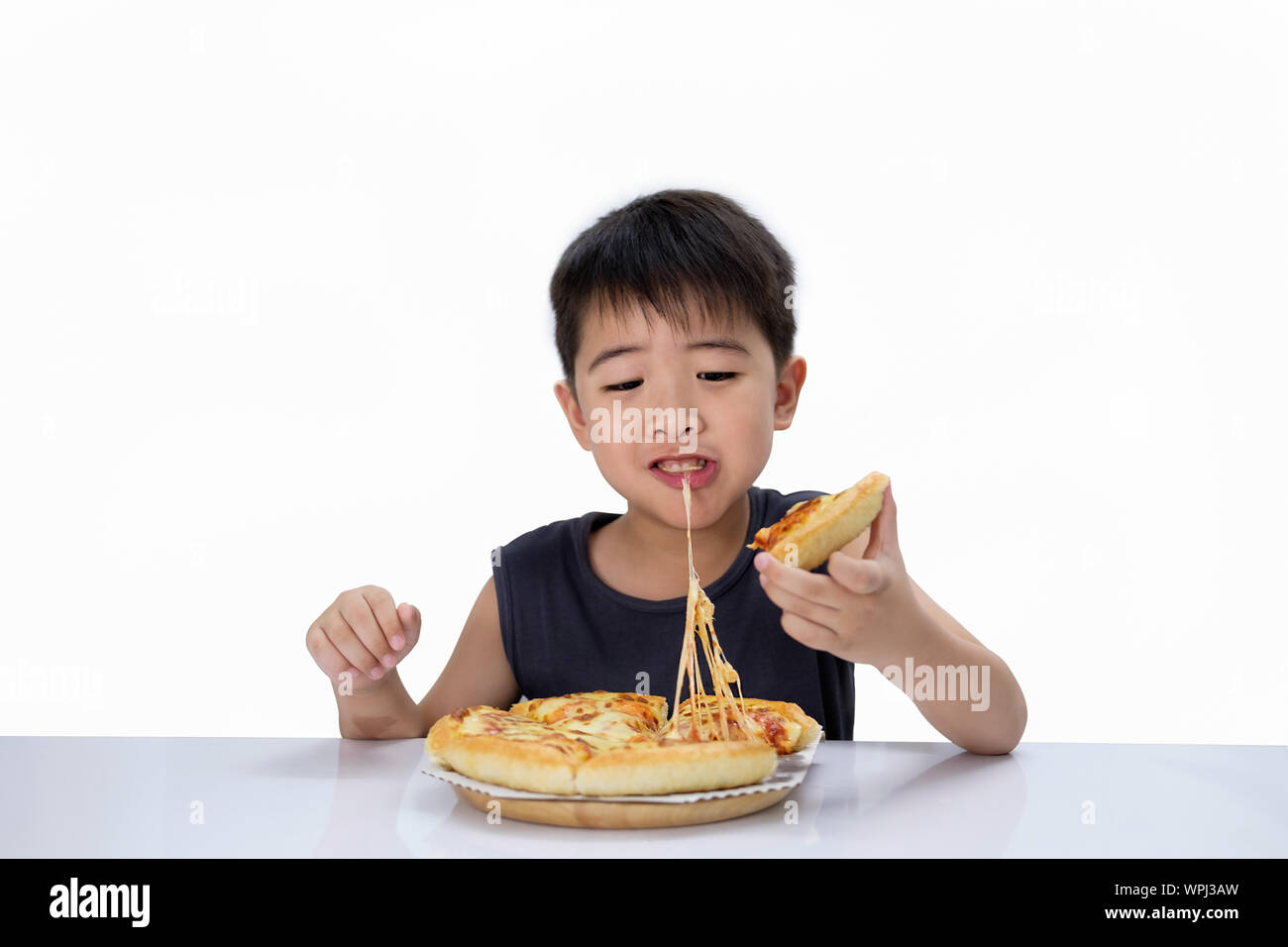 Asian boy is happy to eat pizza with a hot cheese melt stretched on a wooden pad.  Isolated over white. Stock Photo