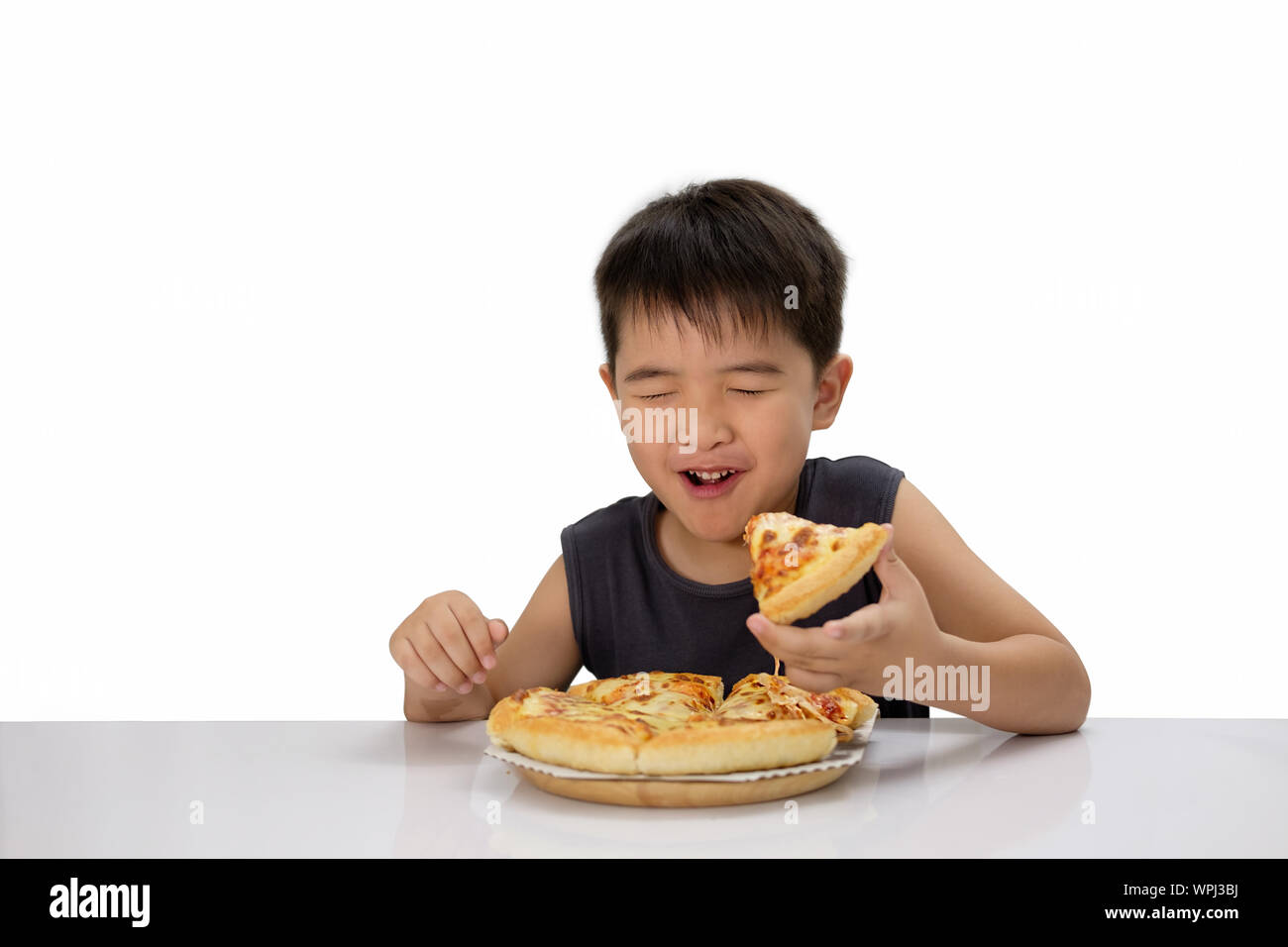 Asian boy is happy to eat pizza with a hot cheese melt stretched on a wooden pad.  Isolated over white. Stock Photo