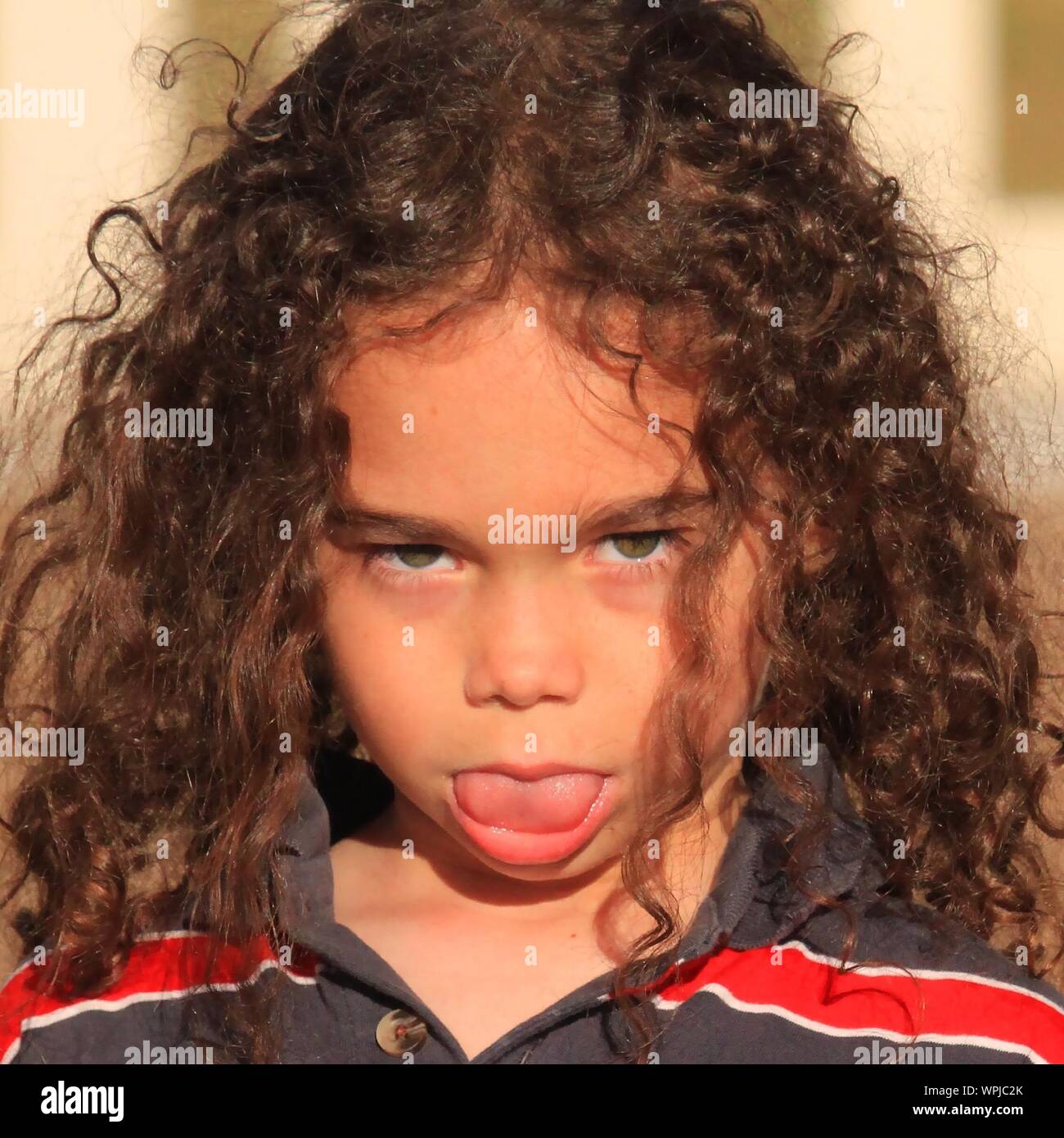 Close-up Portrait Of Girl Sticking Out Tongue Outdoors Stock Photo