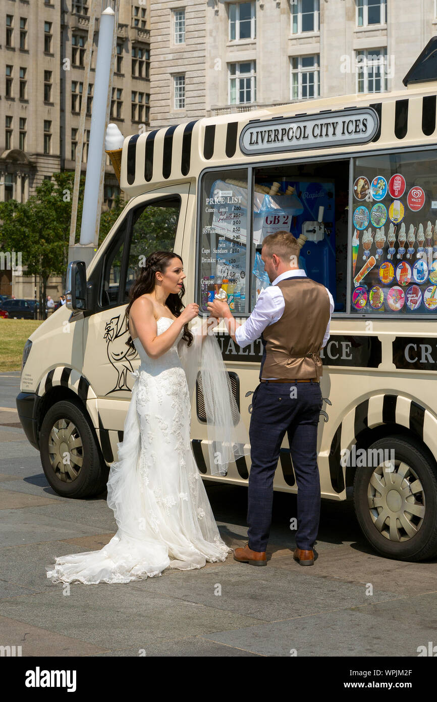 Newly married couple enjoying a 99 ice cream cone on Liverpool seafront. England UK Stock Photo