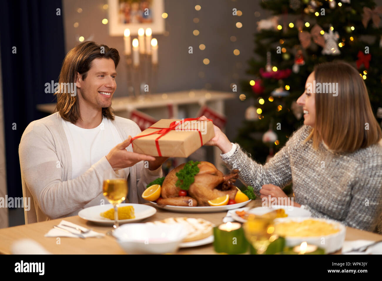 Beautiful couple sharing presents during Christmas dinner Stock Photo