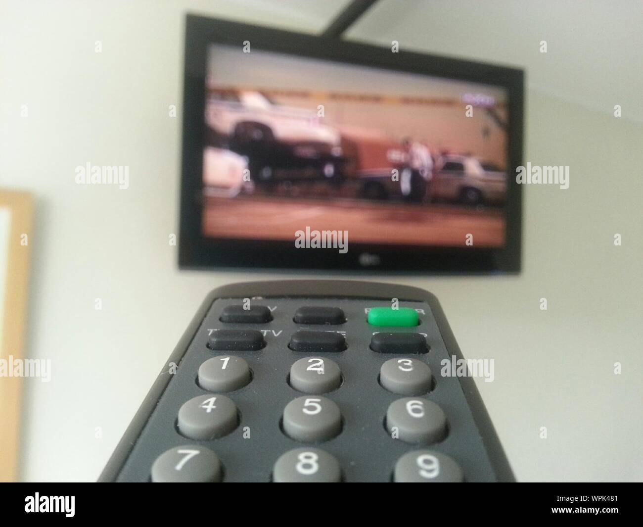 Close-up Of Remote Control Against Television Set At Home Stock Photo